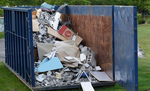 Skip hire yard with skips and staff preparing a skip for transport