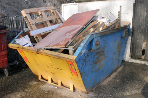 Worker inspecting a skip and preparing documentation on site